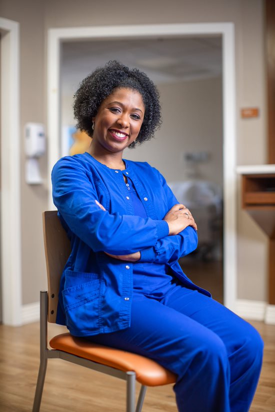 Person sitting and smiling in what appears to be Nurse scrubs.